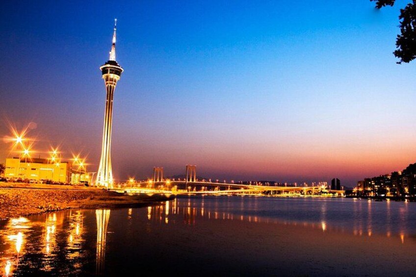 A lit tower, a bridge, and a calm river at dusk. 2