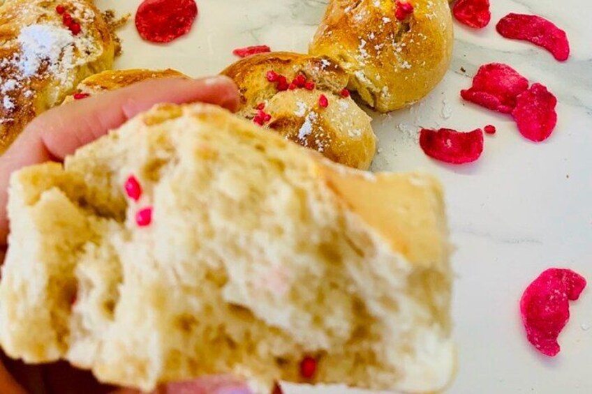 A close-up of a pastry with a flaky texture and sprinkled with red and white toppings. 2