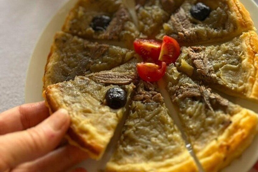 En pizza med skiver og topping af kød og oliven. 5