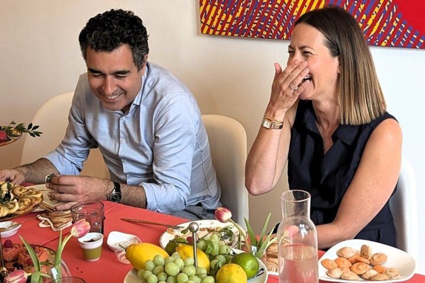 Two people sitting at a table with food and drinks. 1