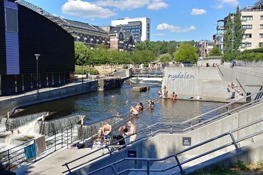 A public swimming area with people in the water, a waterfall feature, and a building labeled 'hydalen'. 5
