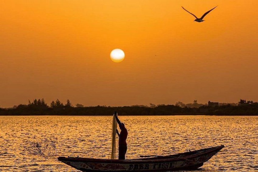 Un atardecer sobre un cuerpo de agua con un barco y una persona de pie en él. 5