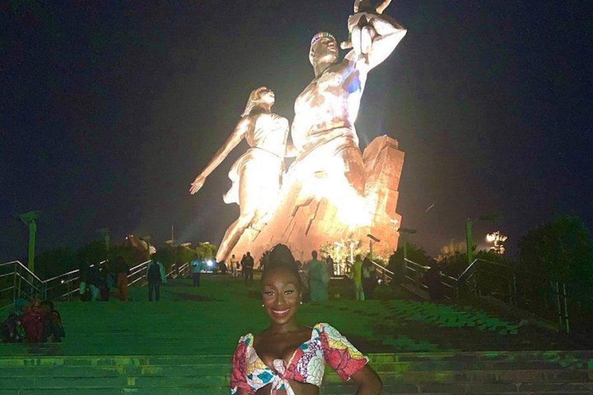 A nighttime scene with a statue illuminated by lights, a person in the foreground, and a staircase leading up to the statue. 1