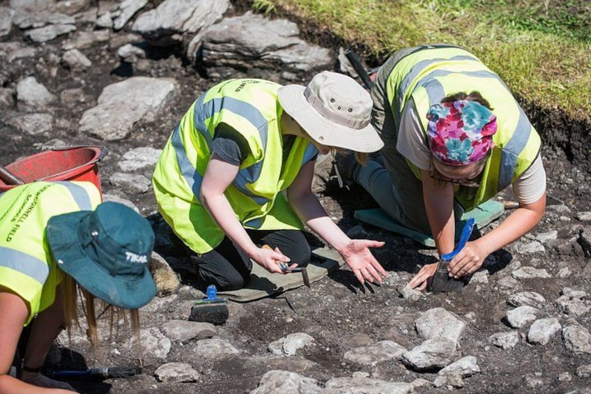 Three people wearing safety vests and hats, examining the ground. 3