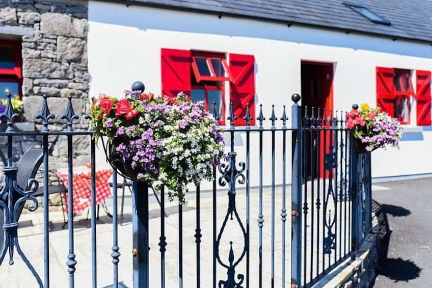 A white building with red shutters, a black wrought iron fence, and flower baskets. 4