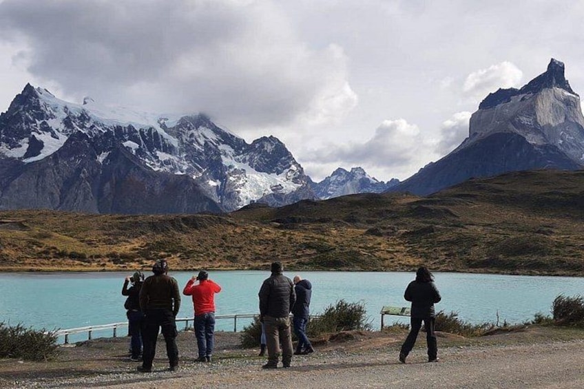 Un groupe de personnes se tient près d’un lac, avec des montagnes en arrière-plan. 3