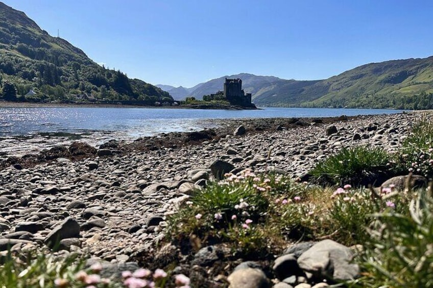 A rocky shoreline with a castle ruin on a hill in the distance. 3