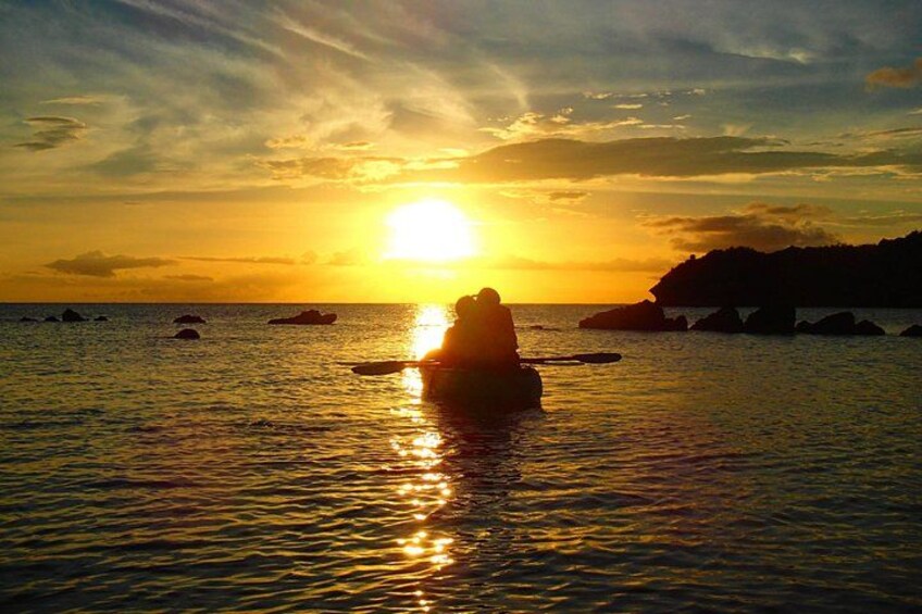 En solnedgång över havet, med en person som paddlar kajak. 4
