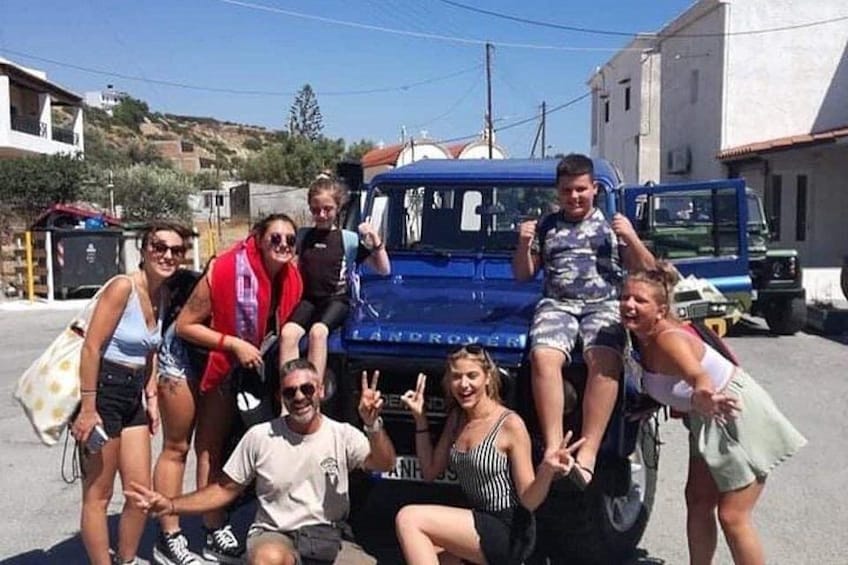 A group of people posing in front of a blue truck with a license plate. 4