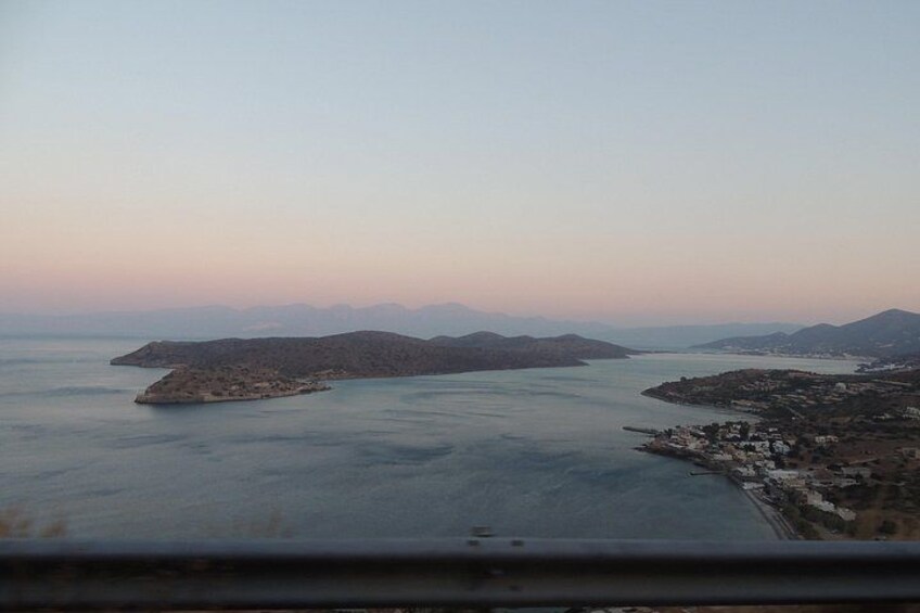 A coastal landscape with a small island, calm sea, and distant mountains. 3