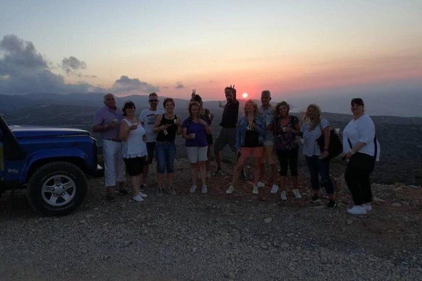 A group of people standing on a rocky outcrop with a sunset in the background. 1