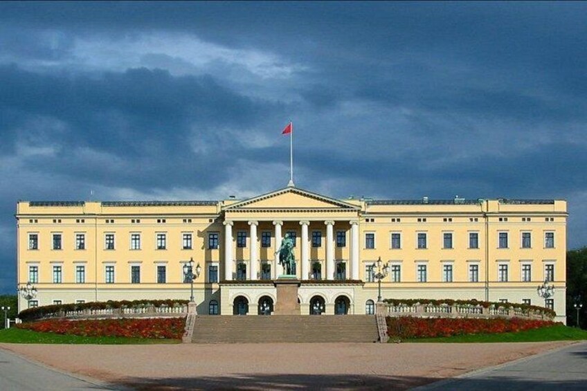 Un edificio grande y amarillo con una entrada central, columnas y una bandera en la parte superior. 5