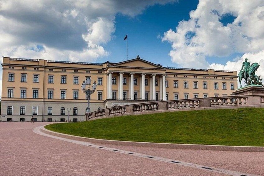 A large neoclassical building with a central entrance, a statue, and a flagpole. 3