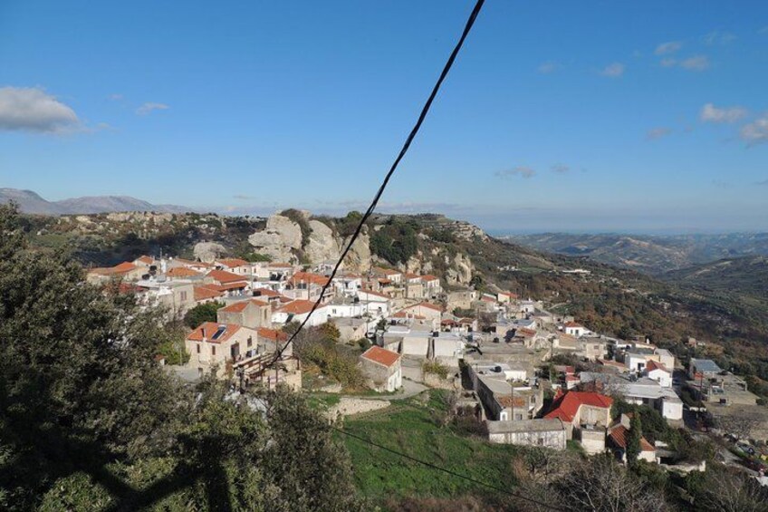 A village with red-roofed buildings nestled in a valley, surrounded by hills and mountains. 2