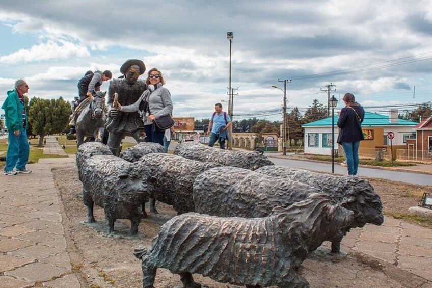 A group of people observing a sculpture of a man with a horse and sheep. 4