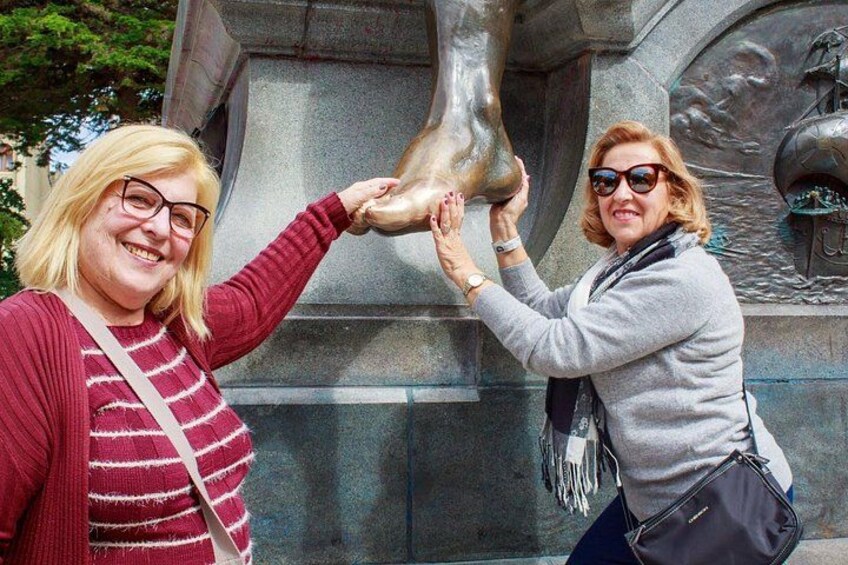 Two people interacting with a bronze statue of a horse's head. 3