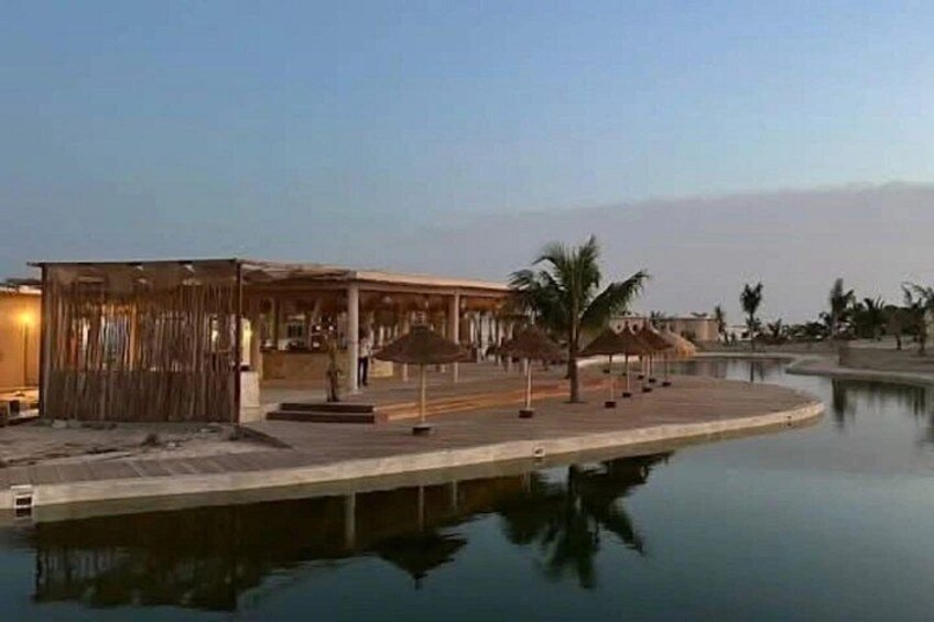Un bâtiment situé au bord de l’eau, doté d’une piscine, de palmiers et surplombant un ciel dégagé. 2