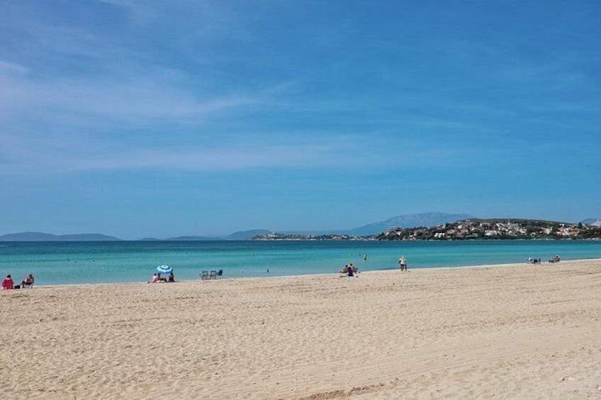 A beach with people, a clear sky, and distant hills. 3