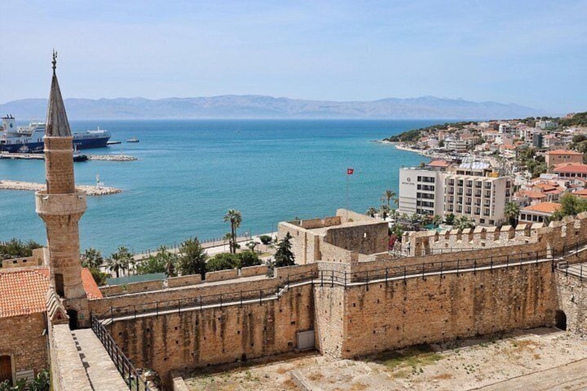 A coastal city with a prominent tower, a fortified wall, and a clear view of the sea. 5
