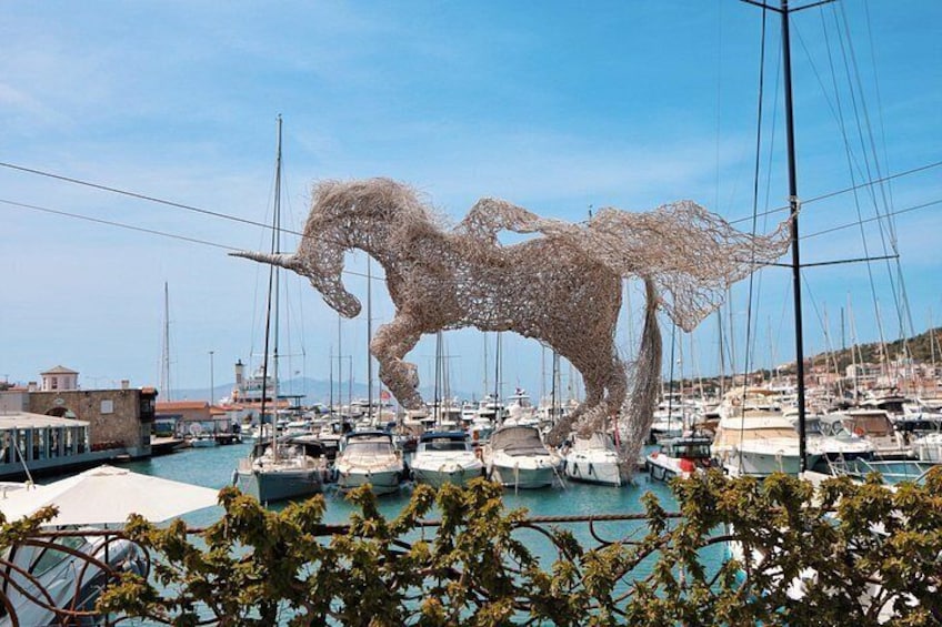 A marina with numerous boats, a large sculpture of a horse, and a clear blue sky. 4