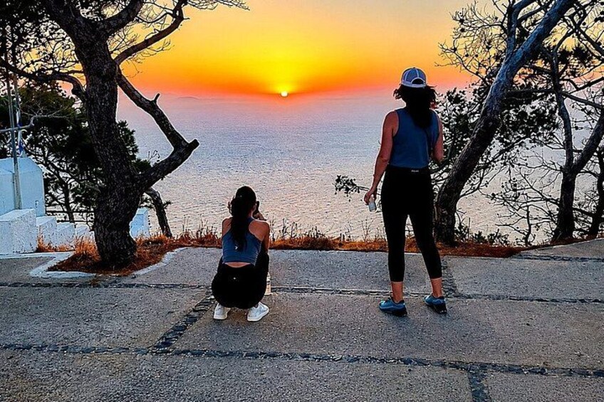 Two people standing on a road overlooking a sunset over the sea. 3
