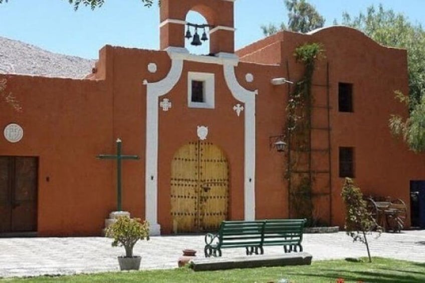 A building with a large wooden door, a bell tower, and a cross. 5