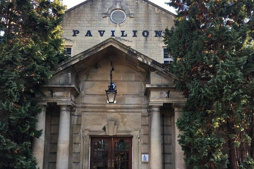 Ein Gebäude mit dem Schriftzug 'PAVILION' über dem Eingang, umgeben von Bäumen. 3