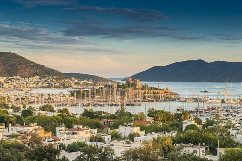 Une ville côtière dotée d’un port de plaisance rempli de bateaux, bordée de collines et comprenant des immeubles d’habitation. 2