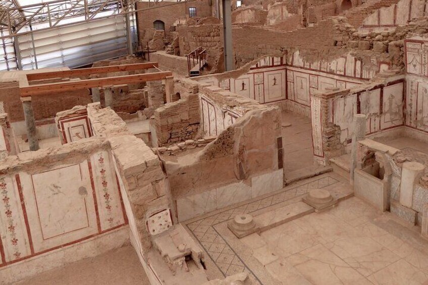 Et arkæologisk område med gamle ruiner, herunder stensrukturer og mure med rødmalede dekorationer. 5