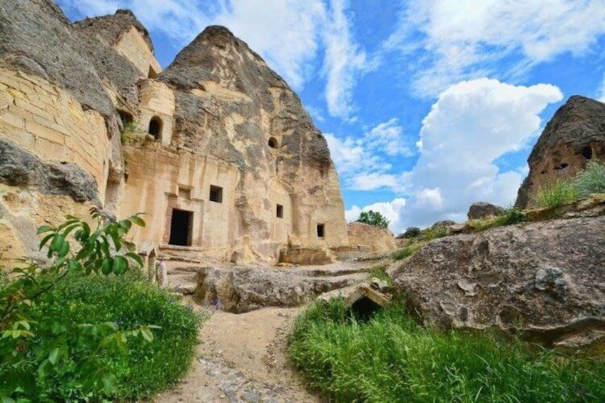 Ancient rock-cut architecture with a narrow path leading to a building with multiple doorways. 5