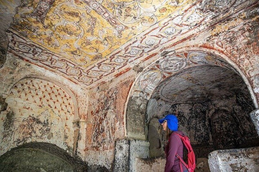 A person exploring an ancient, ornately decorated underground chamber with intricate wall and ceiling designs. 3