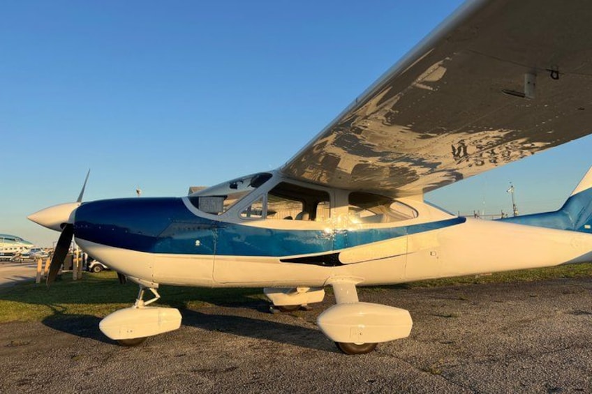 A small aircraft parked on a tarmac with a clear sky in the background. 3