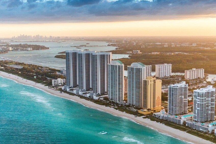 A coastal cityscape with high-rise buildings, a beach, and a marina. 4