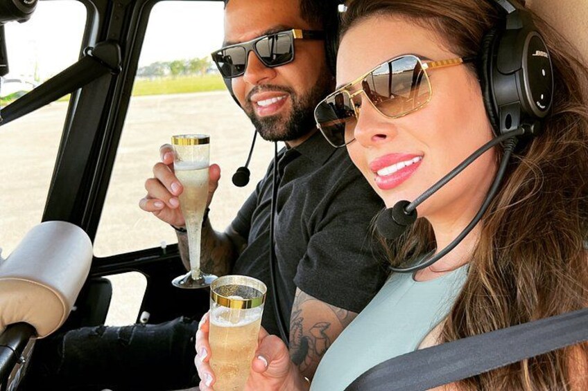 Two people in a vehicle, one holding a glass of champagne. 2