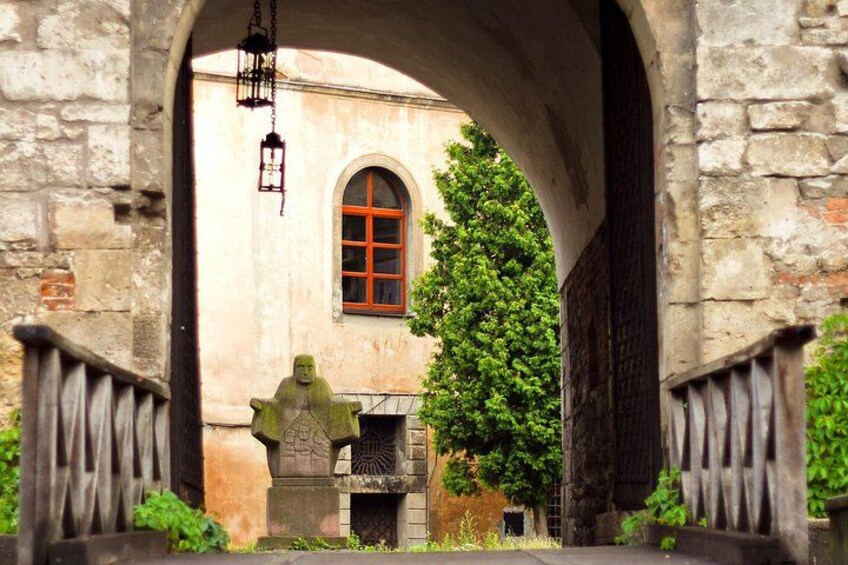 An arched stone doorway, a statue, and a building with a red window. 2
