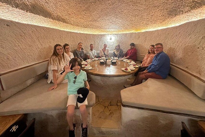 A group of people seated around a round table in a room with a textured, cave-like ceiling. 3