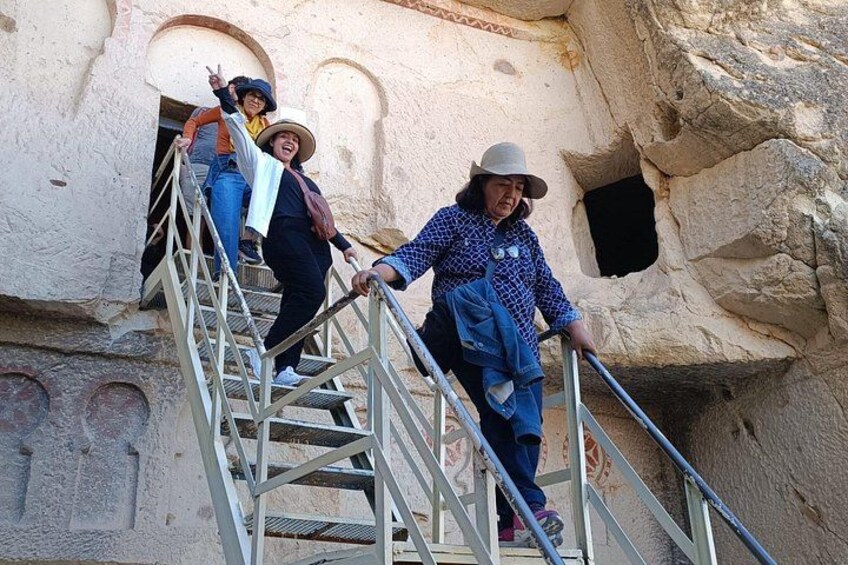 People ascending a metal staircase in a rocky, cave-like environment. 3
