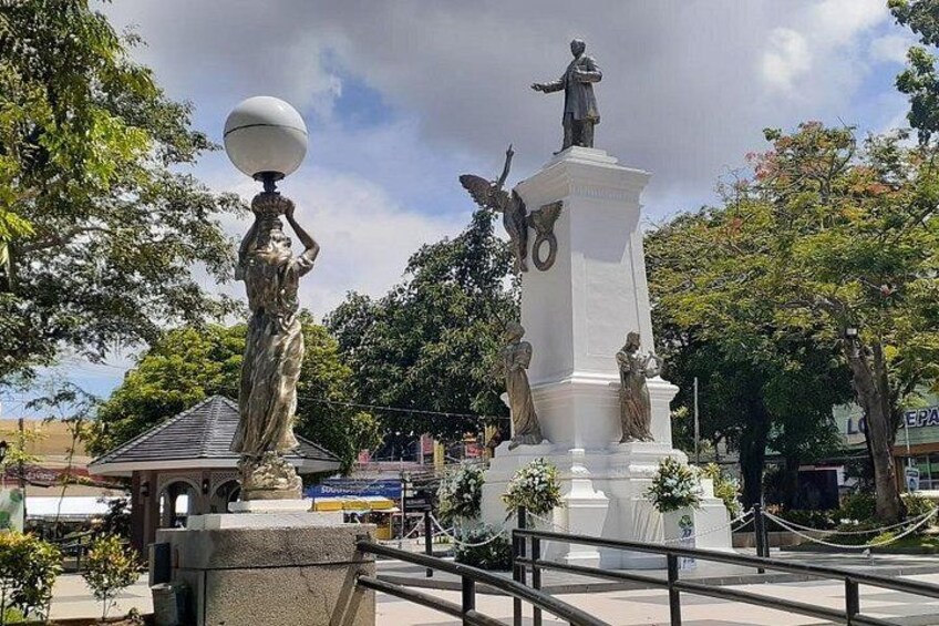 En statue af en kvinde med en globus, et monument med en figur øverst, og en bygning i baggrunden. 4