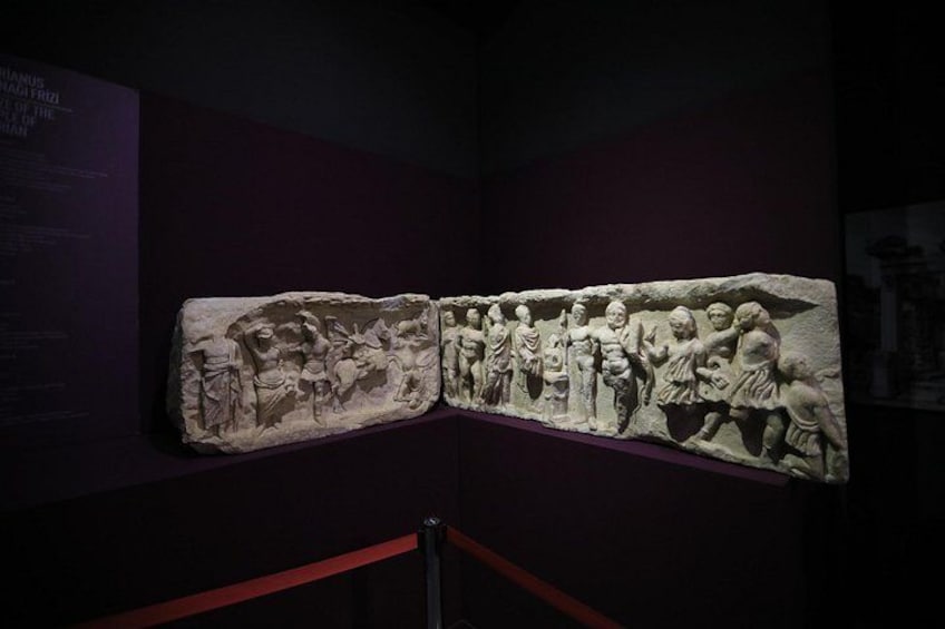 En stentavlerelief med figurer i forskellige positurer, udstillet på et museum. 5