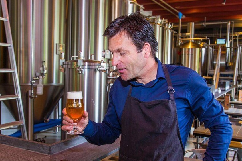 A person in a brewery holding a glass of beer. 4