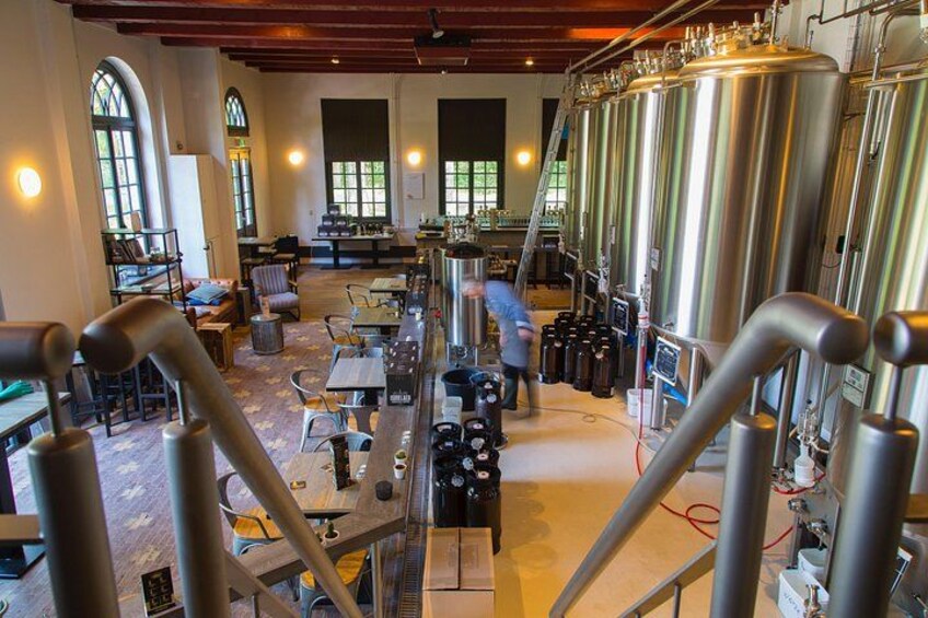 A brewery interior with stainless steel tanks, wooden beams, and a spacious layout. 3