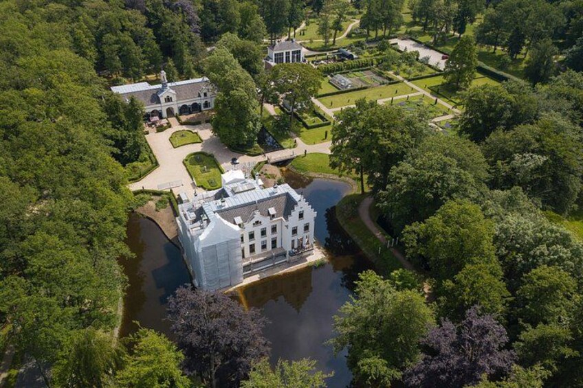 A large estate with a central building surrounded by a moat, lush greenery, and formal gardens. 5