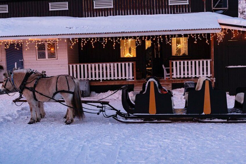 A snow-covered house with a sleigh pulled by two horses. 2