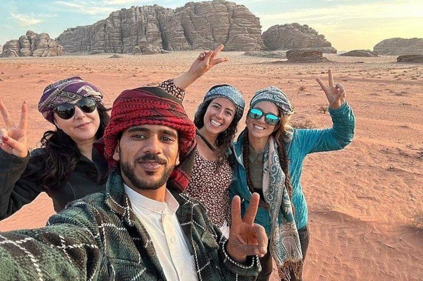 A group of people in a desert landscape with rock formations in the background. 2