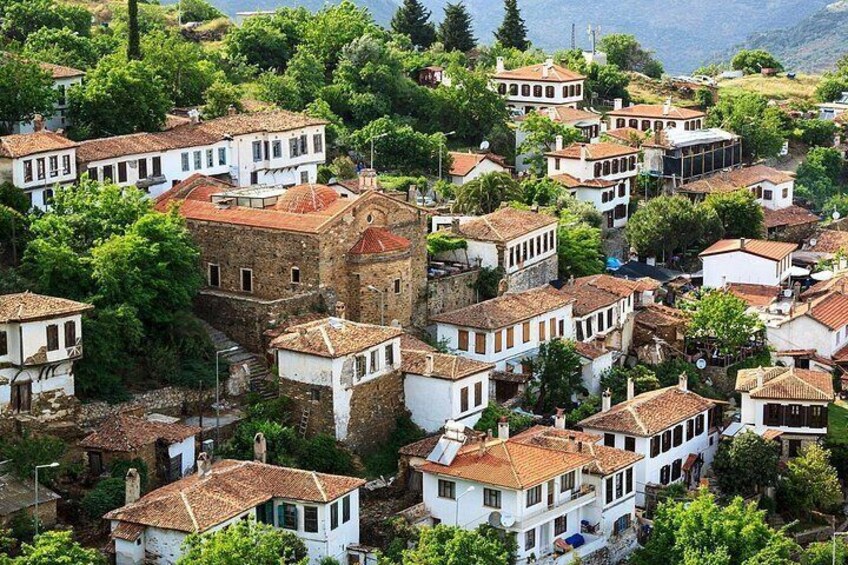 A hillside village with traditional buildings, a prominent stone tower, and lush greenery. 4