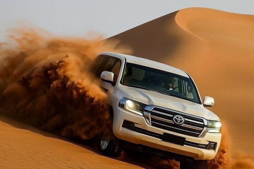 Een witte SUV rijdt door een woestijn met zandduinen. 2