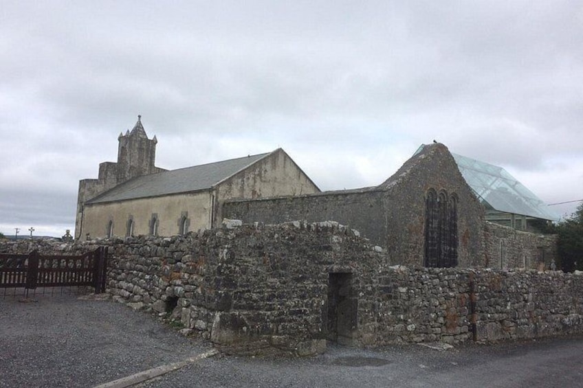 An old stone building with a glass roof, a stone wall, and a metal gate. 4