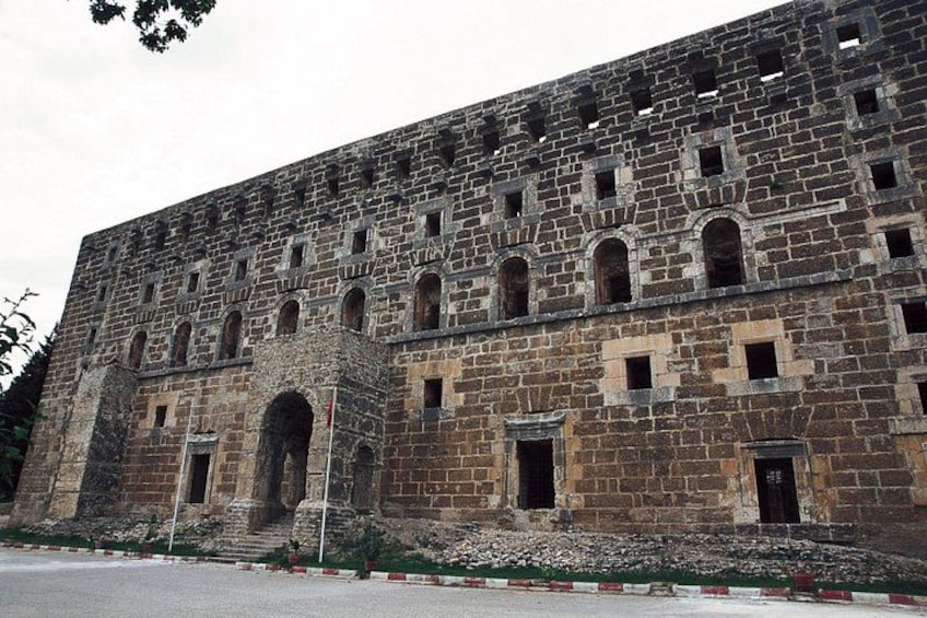 A large, historic stone building with multiple arched windows and a central entrance. 5
