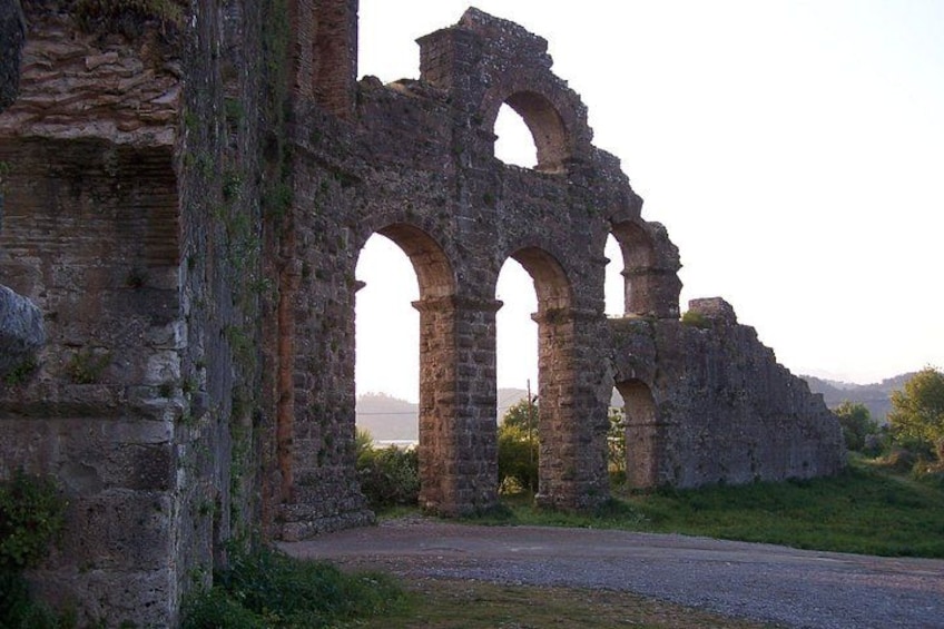 Ancient stone ruins with arches and columns, surrounded by greenery and a clear sky. 4