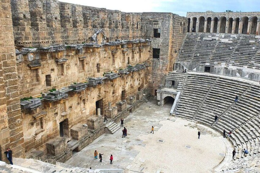 Un ancien amphithéâtre avec des gradins en pierre et quelques personnes qui se promènent. 1